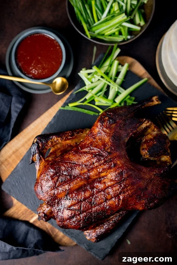 Crispy Homemade Roast Duck Recipe for Perfectly Crunchy Skin 2 Overhead of Chinese crispy duck on a dark background with plum sauce and greens