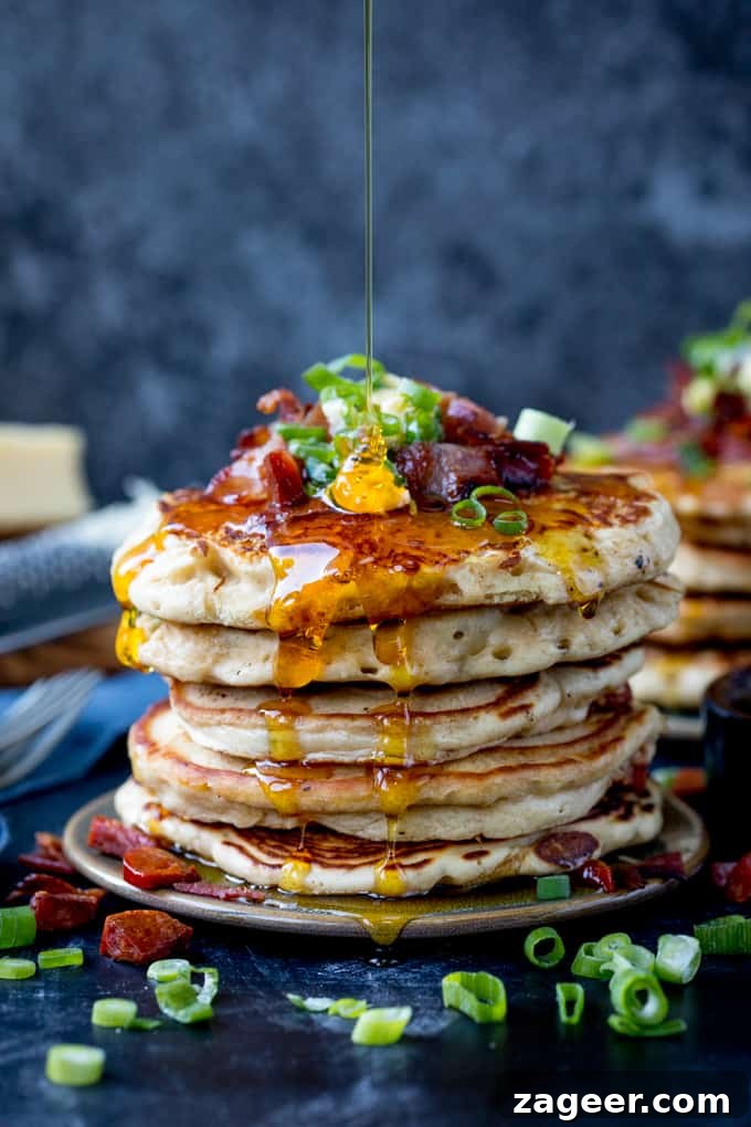 Savory Dinner Pancakes with Spicy Chilli Butter 2 Savoury pancakes stacked up on a plate and topped with bacon, chilli butter and spring onions. Golden syrup being drizzled on.