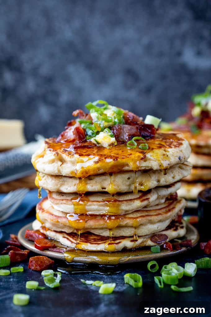 Savory Dinner Pancakes with Spicy Chilli Butter 7 Stack of savoury pancakes against a dark background. Pancakes are topped with bacon, chilli butter and spring onions.