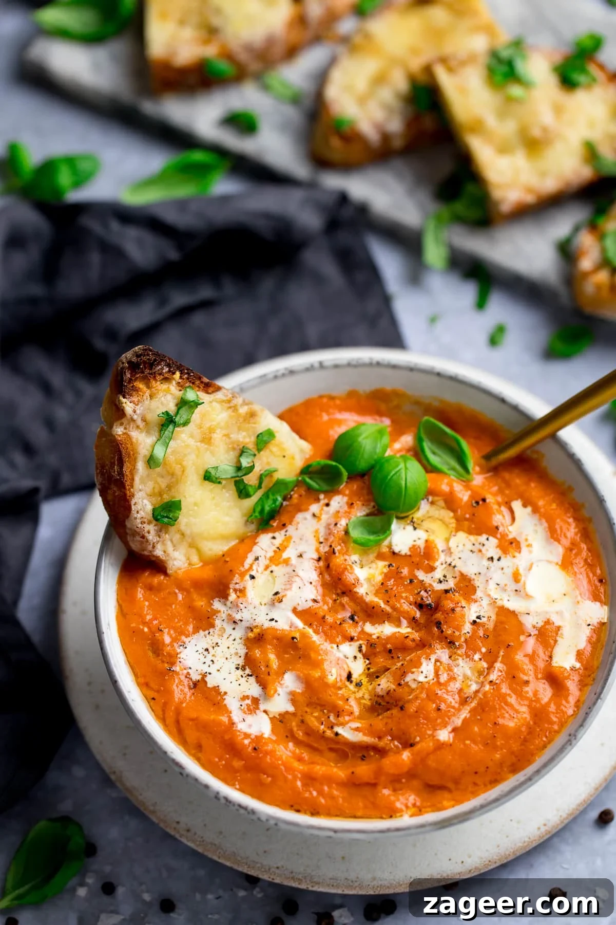 Homemade Creamy Tomato Soup Recipe from Scratch 2 Bowl of rich tomato soup with a slice of basil-cheese toast in it, and more slices of cheese toast on the side.
