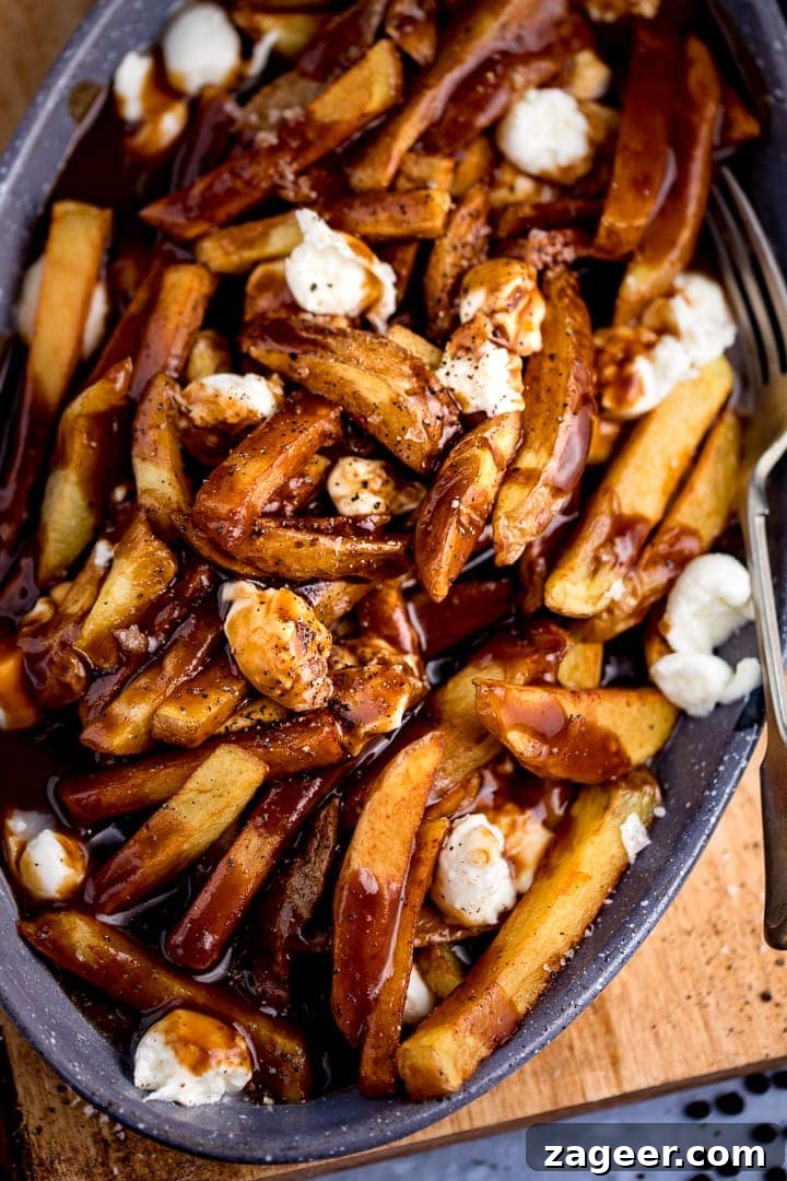 Classic Canadian Poutine Recipe: How to Make Authentic Poutine at Home 6 overhead image of Poutine in a grey dish on a wooden board