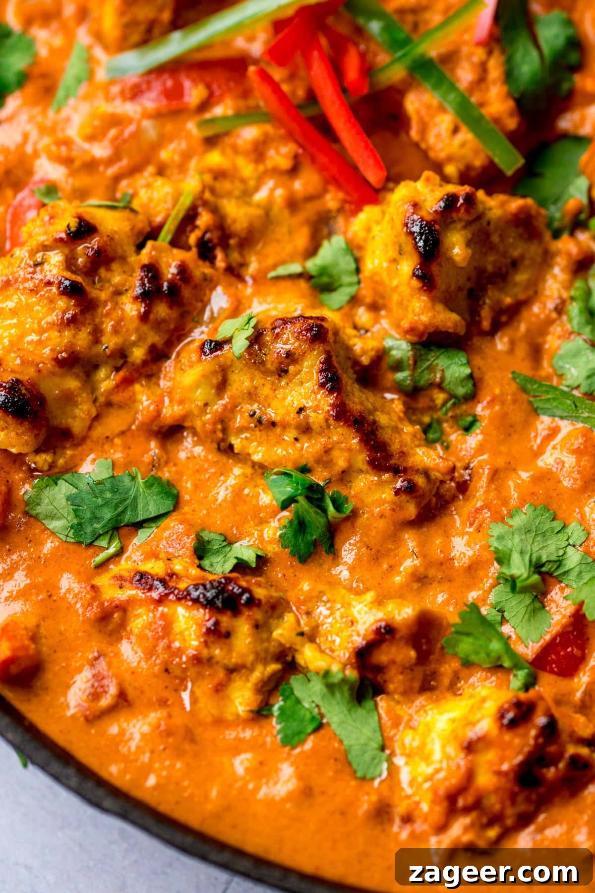 Authentic Chicken Tikka Masala Recipe for Tender, Creamy Curry 7 Close-up of chicken tikka masala with chargrilled chicken pieces in creamy masala curry sauce, garnished with fresh coriander and sliced chillies.