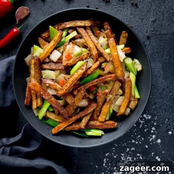 Crispy Pizza Fries Recipe: Loaded Seasoned Potato Bites 9 Overhead picture of a dark bowl full of salt and pepper chips sat on a blue background.