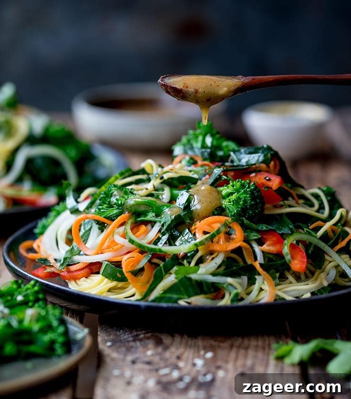Winter Vegetable Noodle Salad with Citrus-Ginger Dressing 2 miso dressing being drizzled onto a noodle salad on a wooden background