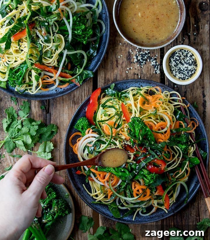 Winter Vegetable Noodle Salad with Citrus-Ginger Dressing 5 Overhead image of miso dressing being drizzled on a noodle salad on a dark background