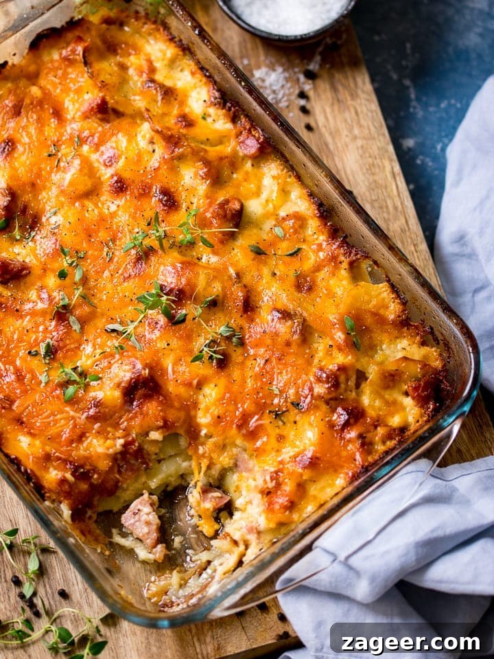 Creamy Scalloped Potatoes with Ham and Cheese Bake 2 Scalloped potatoes with ham in a dish on a wooden board