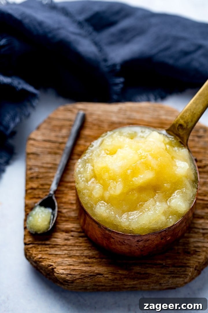 Homemade Applesauce from Scratch: Simple, Flavorful Recipe 5 Apple sauce in a copper pan on a wooden board next to a blue teatowel