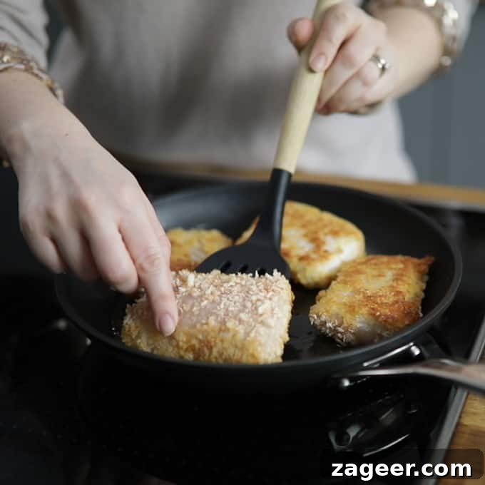 Crispy Fish Sandwich with Shoestring Fries Recipe 4 Frying pan with 4 breaded haddock fillets frying. One is being turned over with a spatula.
