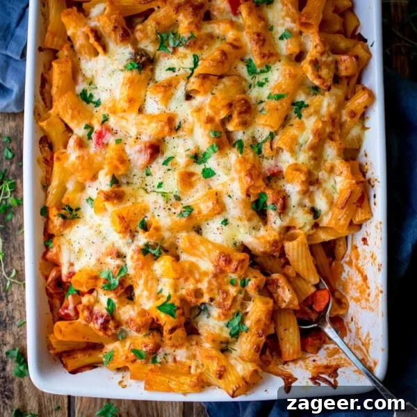 Cheesy Tomato and Tuna Pasta Bake Recipe 10 A cheesy chicken pasta bake served in a white dish, topped with melted cheese and fresh herbs.