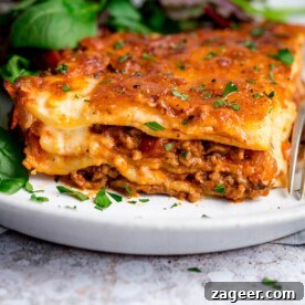 Pantry-Friendly Recipes: Delicious Meals from Store Cupboard Staples 8 Portion of lasagne on a white plate with salad in the background