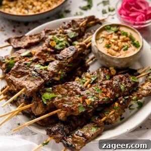 Grilled Beef Satay Recipe: Tender Skewers with Peanut Sauce 11 beef satay on wooden skewers on a white plate