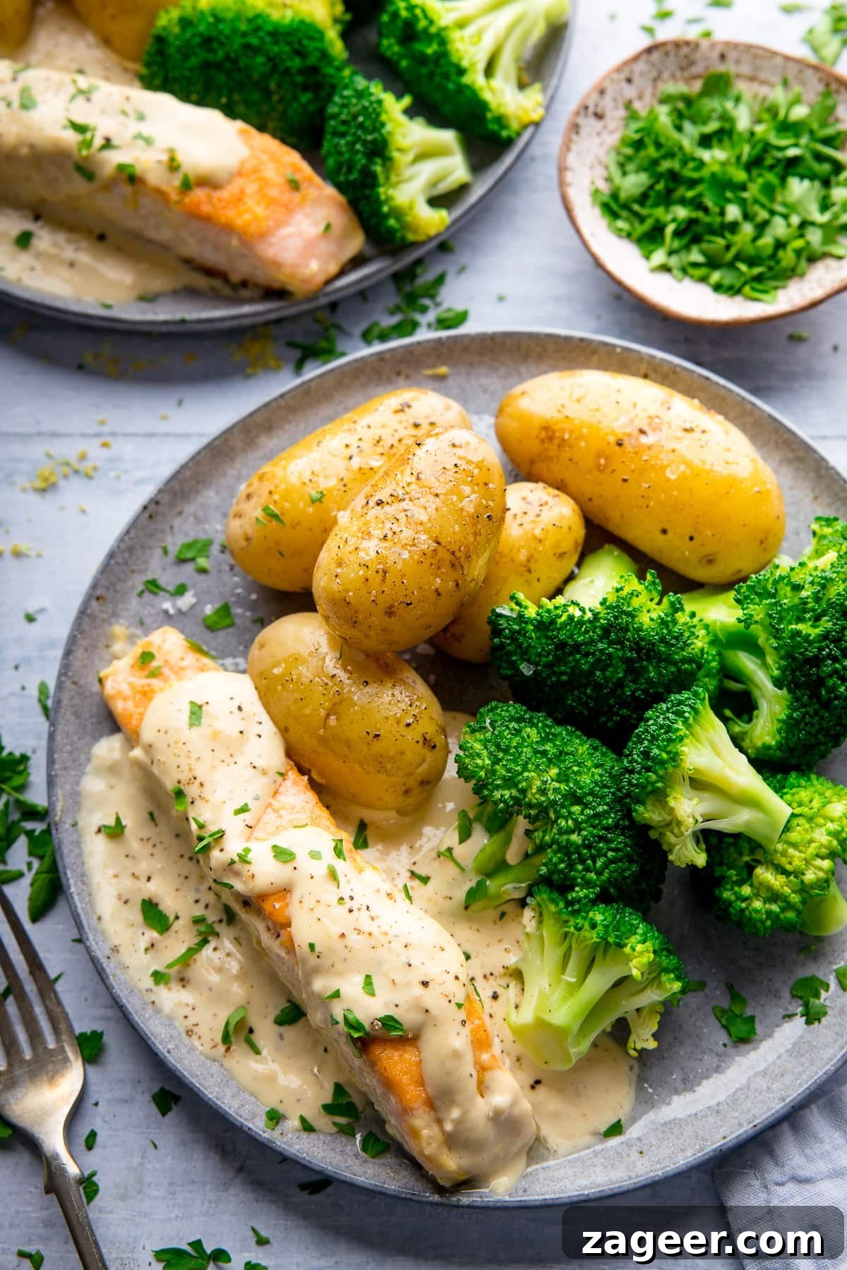 Creamy White Wine Salmon Recipe with Garlic and Herbs 2 Grey plate with salmon drizzled in a creamy sauce served with broccoli and potatoes