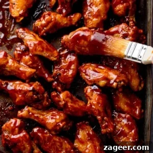 Perfect BBQ Chicken Wings Recipe: Juicy, Crispy & Smoky 10 BBQ chicken wings on a tray with BBQ sauce being brushed on