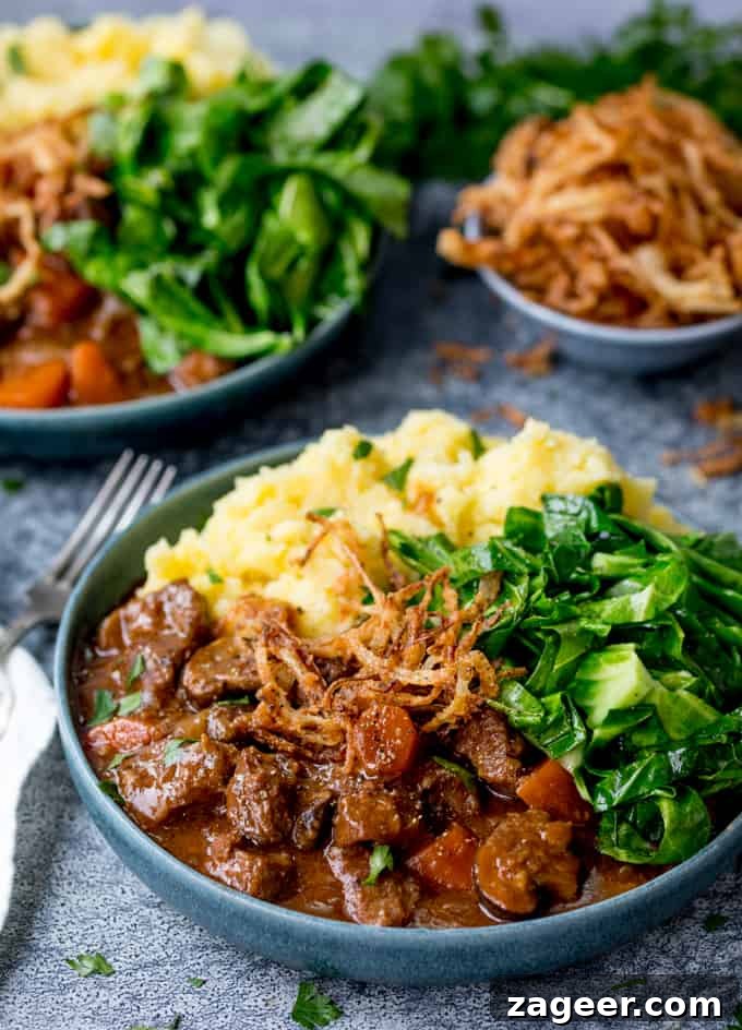 Hearty Beef and Guinness Stew Topped with Crispy Fried Onions 2 Bowl of beef and Guinness Stew with mashed potatoes and green cabbage