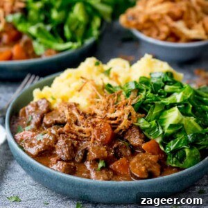 Square image of a bowl of beef and Guinness Stew with mashed potatoes and green cabbage
