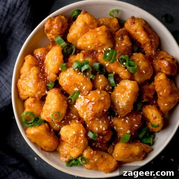 Crispy Homemade Sausage Rolls Recipe for Perfect Party Snacks 14 Close-up overhead square image of a white bowl filled with crispy Air Fryer hot honey chicken bites, garnished with chopped spring onions and sesame seeds.