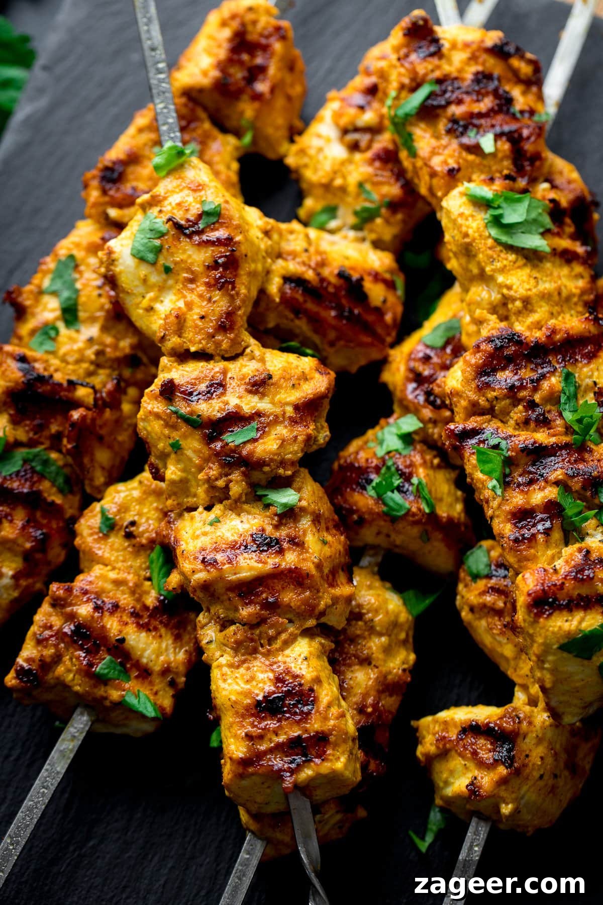 Close up of chicken tikka on metal skewers