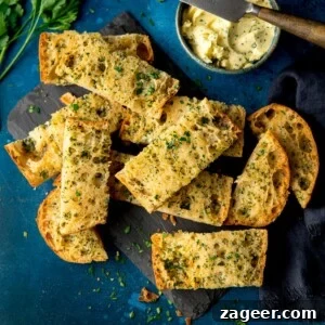Quick Homemade Garlic Bread Recipe for Crispy, Flavorful Slices 8 Sliced of garlic bread on a dark blue background with a bowl of garlic butter and knife at the top of the frame