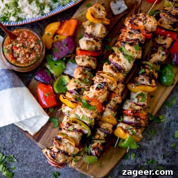Authentic Lamb Barbacoa Recipe — Slow-Cooked Mexican-Style Lamb 13 Square overhead shot of Mexican chicken kebabs piled on a wooden board. Salsa and rice in the background.