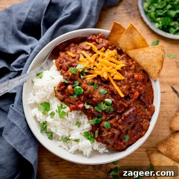 Authentic Lamb Barbacoa Recipe — Slow-Cooked Mexican-Style Lamb 9 A bowl of chilli con carne with kidney beans, ground beef, cheese, and cilantro over white rice. Tortilla chips on the side.