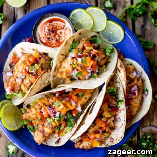Authentic Lamb Barbacoa Recipe — Slow-Cooked Mexican-Style Lamb 10 Overhead square image of 6 crispy fish tacos on a blue plate, topped with pico de gallo and sriracha mayo.