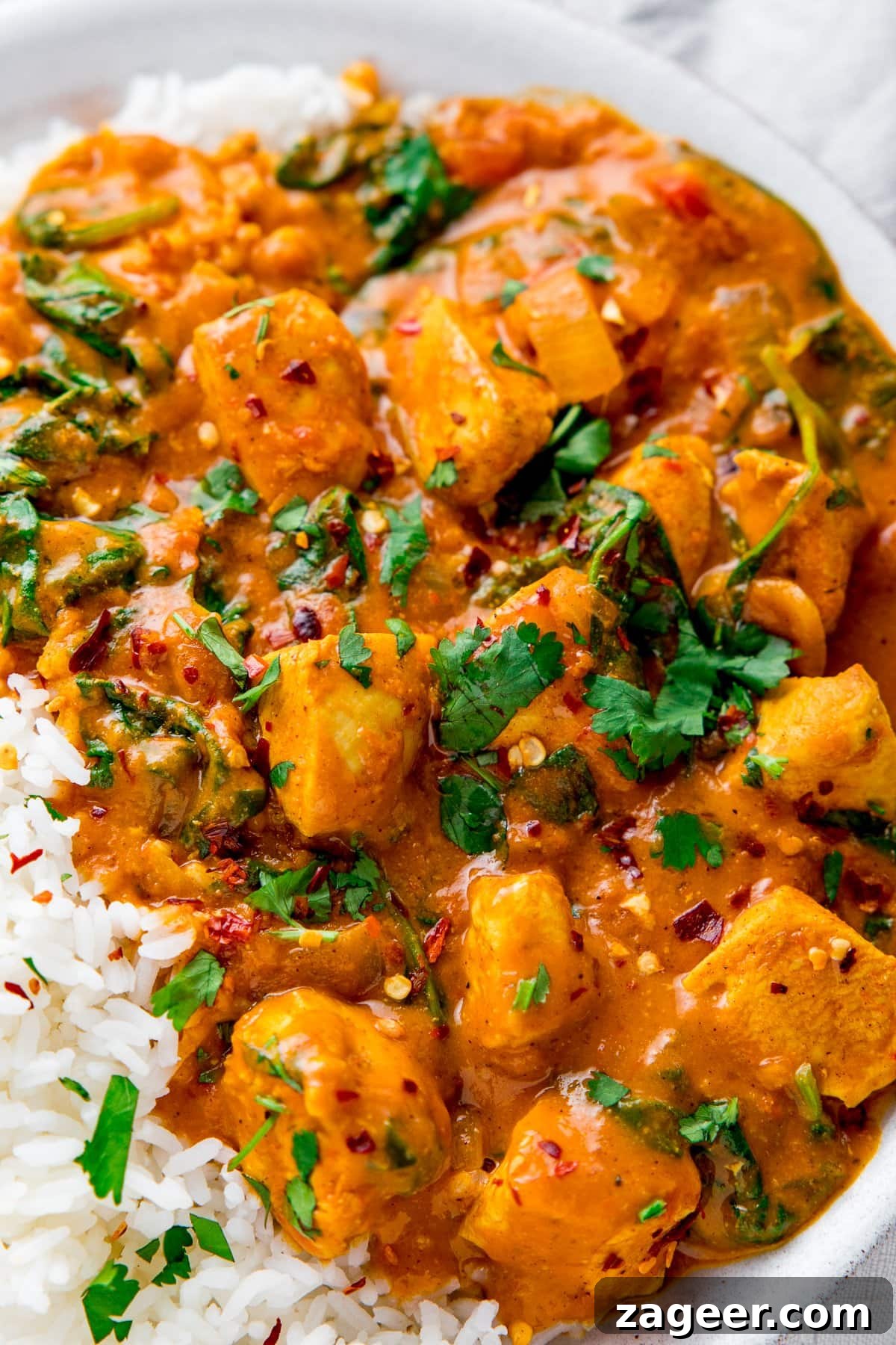 Simple Indian-Style Chicken Curry Recipe for Weeknight Dinners 2 Close up of chicken curry in a white bowl alongside some boiled rice