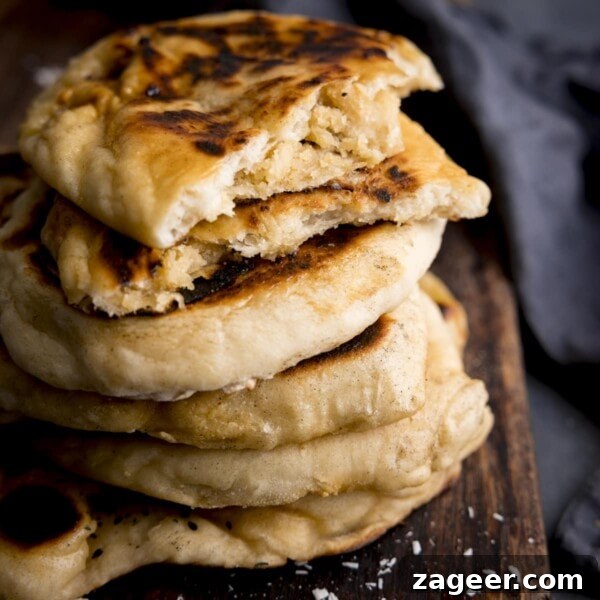 Authentic Pilau Rice Recipe: Aromatic Spiced Pilaf Instructions 14 Close up of a stack of peshwari naan breads on a dark wooden board against a blue background.