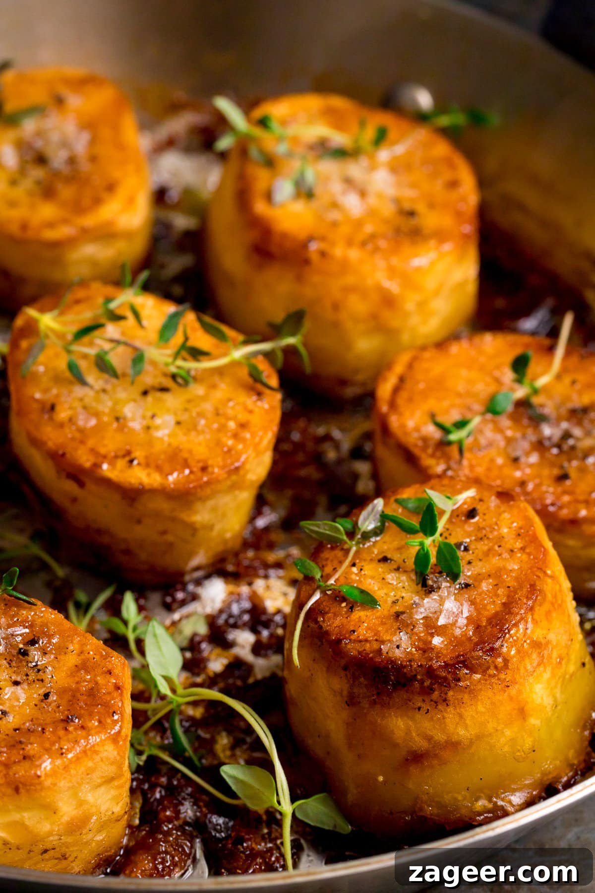 Perfectly Crispy Fondant Potatoes: Classic Oven-Roasted Recipe 2 Close up of fondant potatoes in a frying pan, topped with fresh thyme