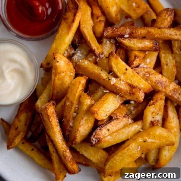 Perfectly Crispy Fondant Potatoes: Classic Oven-Roasted Recipe 11 Air Fryer Chips sprinkled with salt and pepper on a white plate.