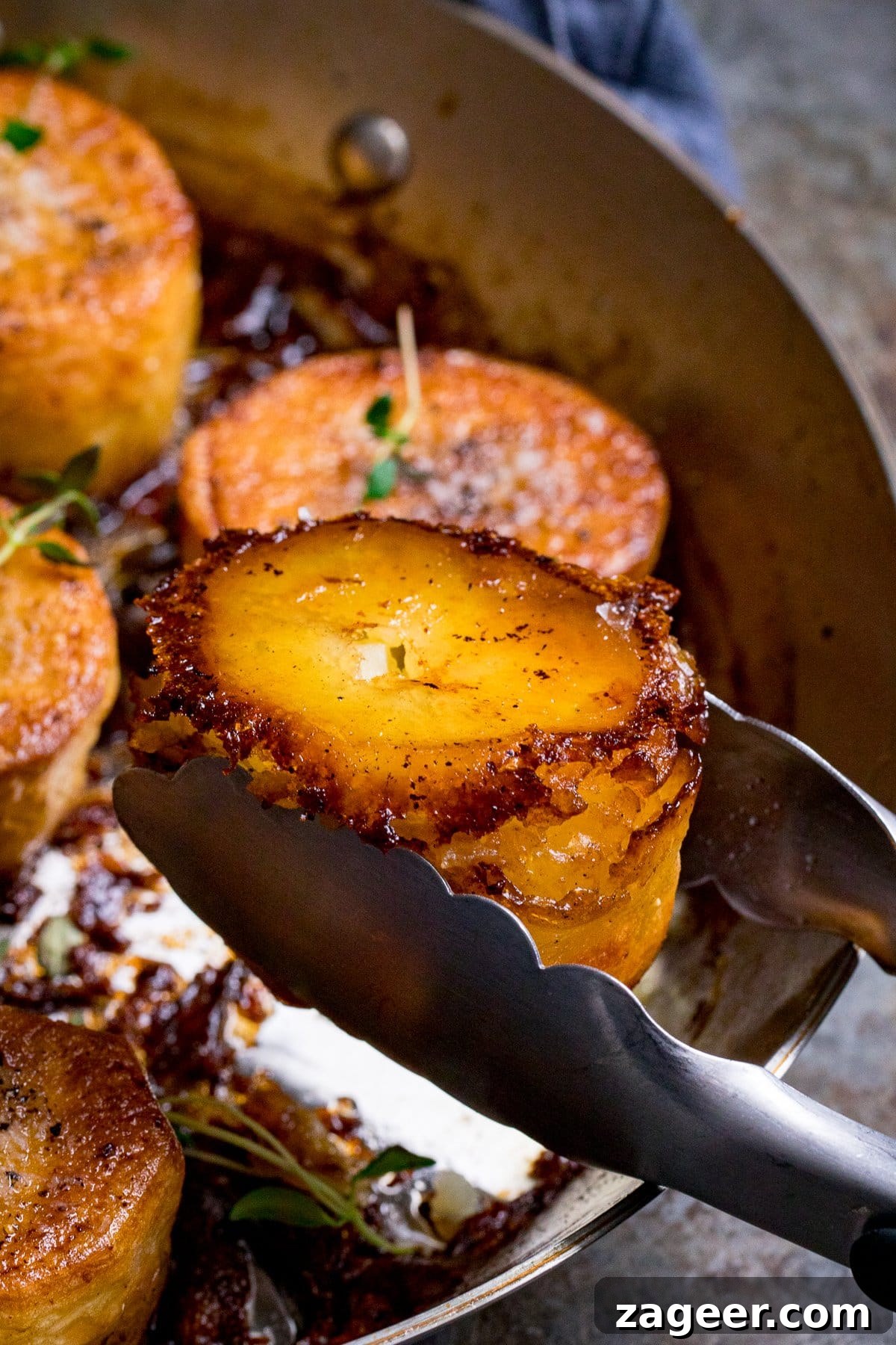 Perfectly Crispy Fondant Potatoes: Classic Oven-Roasted Recipe 7 Close up of a fondant potato being taken from a pan with tongs