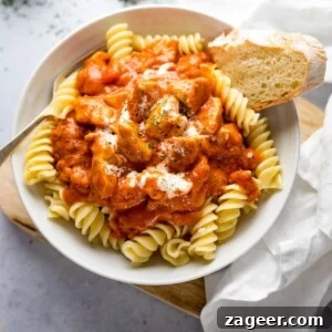 Classic Hungarian Chicken Paprikash Recipe — Creamy Paprika Chicken 8 Chicken Paprikash in a white bowl on top of pasta with a piece of bread in the bowl.
