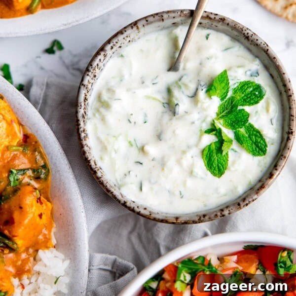 Creamy Chicken Pasanda Recipe: Aromatic Mughlai Curry Guide 10 Raita in a grey bowl with mint leaves on top and bowls of food around the raita
