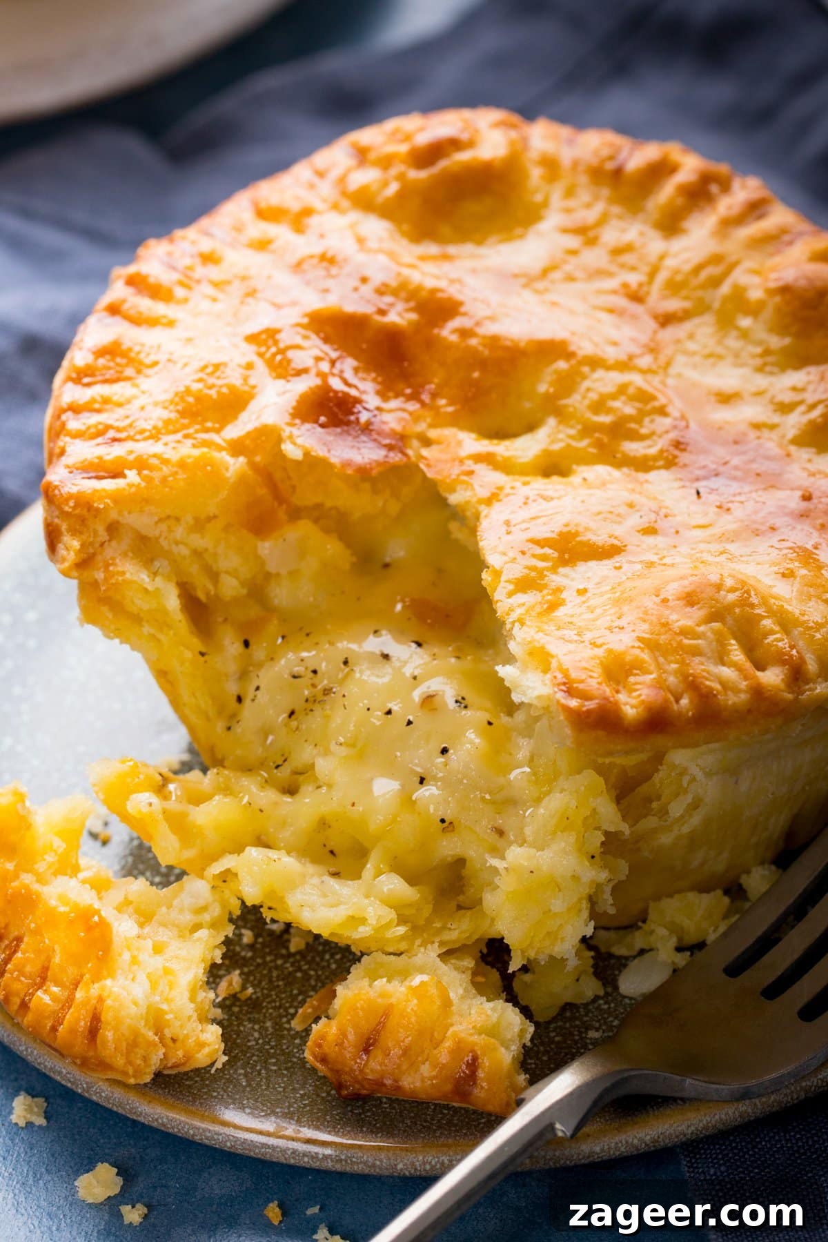 Chip Shop-Style Individual Cheese and Onion Pies 2 Close up of a cheese and onion pie on a plate with a forkful taken out.