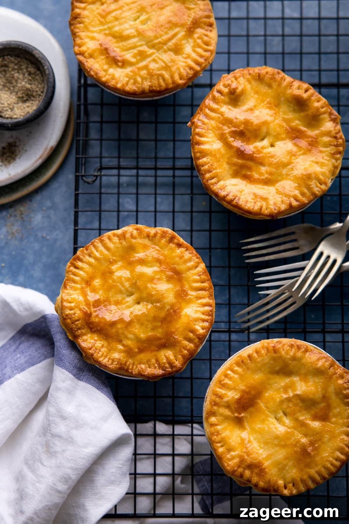 Chip Shop-Style Individual Cheese and Onion Pies 6 Overhead image of 4 cheese and onion pies on a cooling rack on a blue surface.