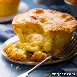 Chip Shop-Style Individual Cheese and Onion Pies 8 Square image of a small cheese and onion pie on a plate with a piece taken out.