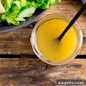 Honey Mustard Salad Dressing in a jar on a wooden table. Part of a bowl of salad just in shot.