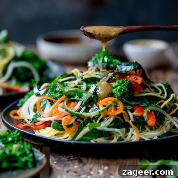 miso dressing being drizzled onto a noodle salad on a dark background