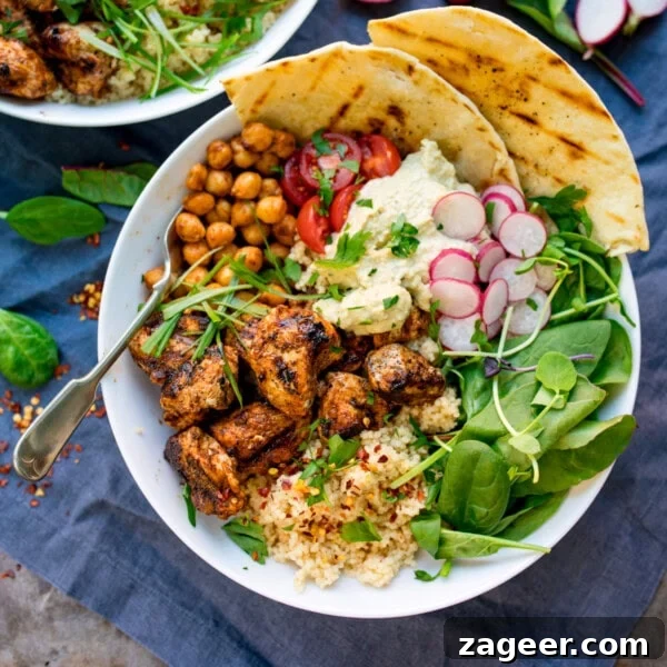 spicy chicken, chickpeas, couscous, leaves, radish, hummus and flatbreads in a bowl