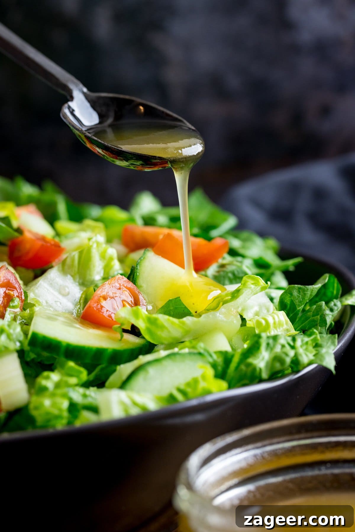 Homemade Honey Mustard Dressing Recipe 8 honey mustard salad dressing being poured off a black spoon onto a bowl of salad.