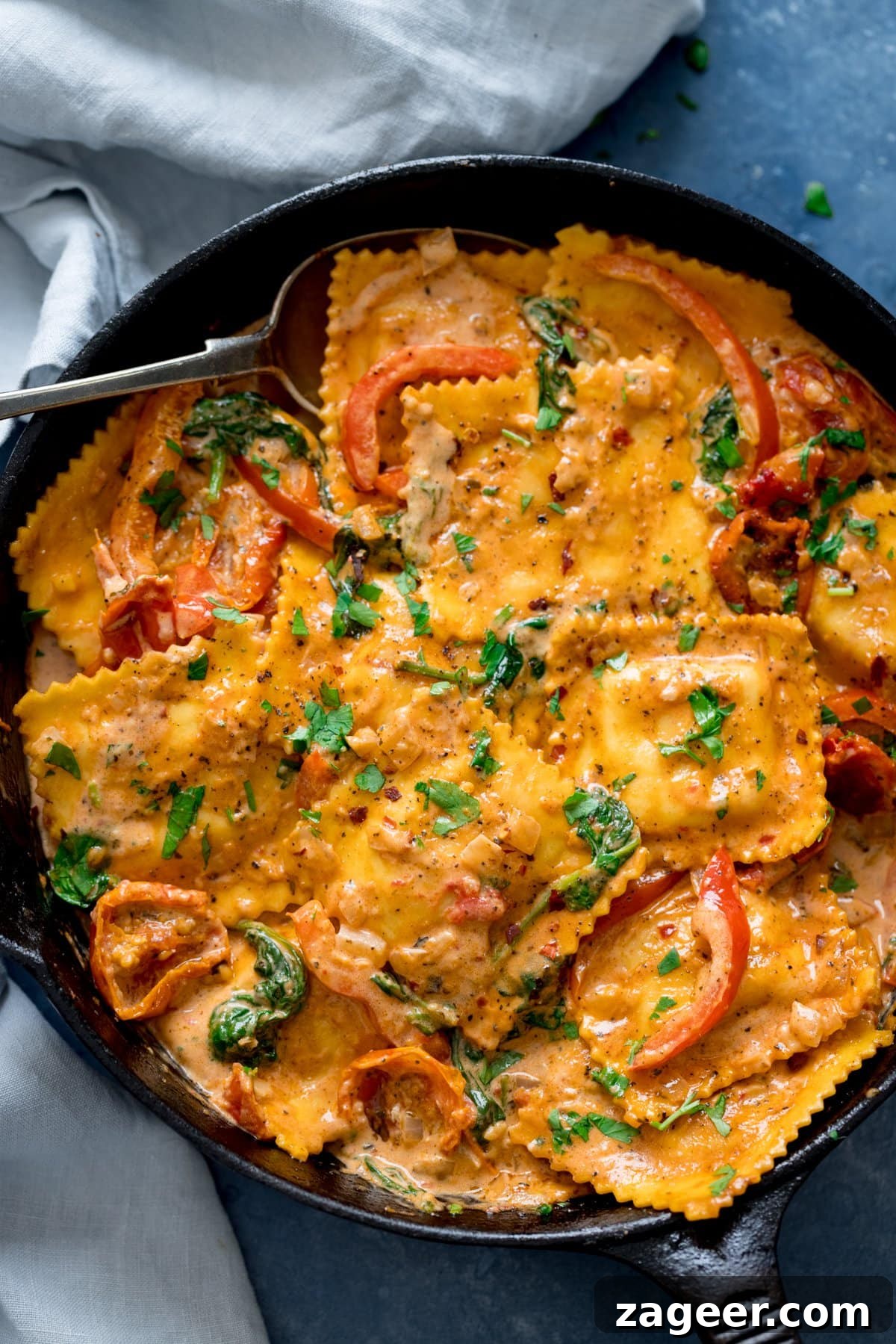 Creamy Tomato Sauce for Ravioli: Quick Weeknight Recipe 5 Black pan filled with ravioli in creamy tomato sauce on a blue background.