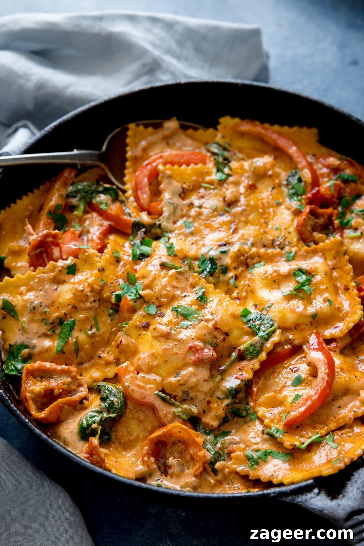 Creamy Tomato Sauce for Ravioli: Quick Weeknight Recipe 7 Creamy tomato ravioli in a dark pan on a light background with a light blue napkin next to the pan.