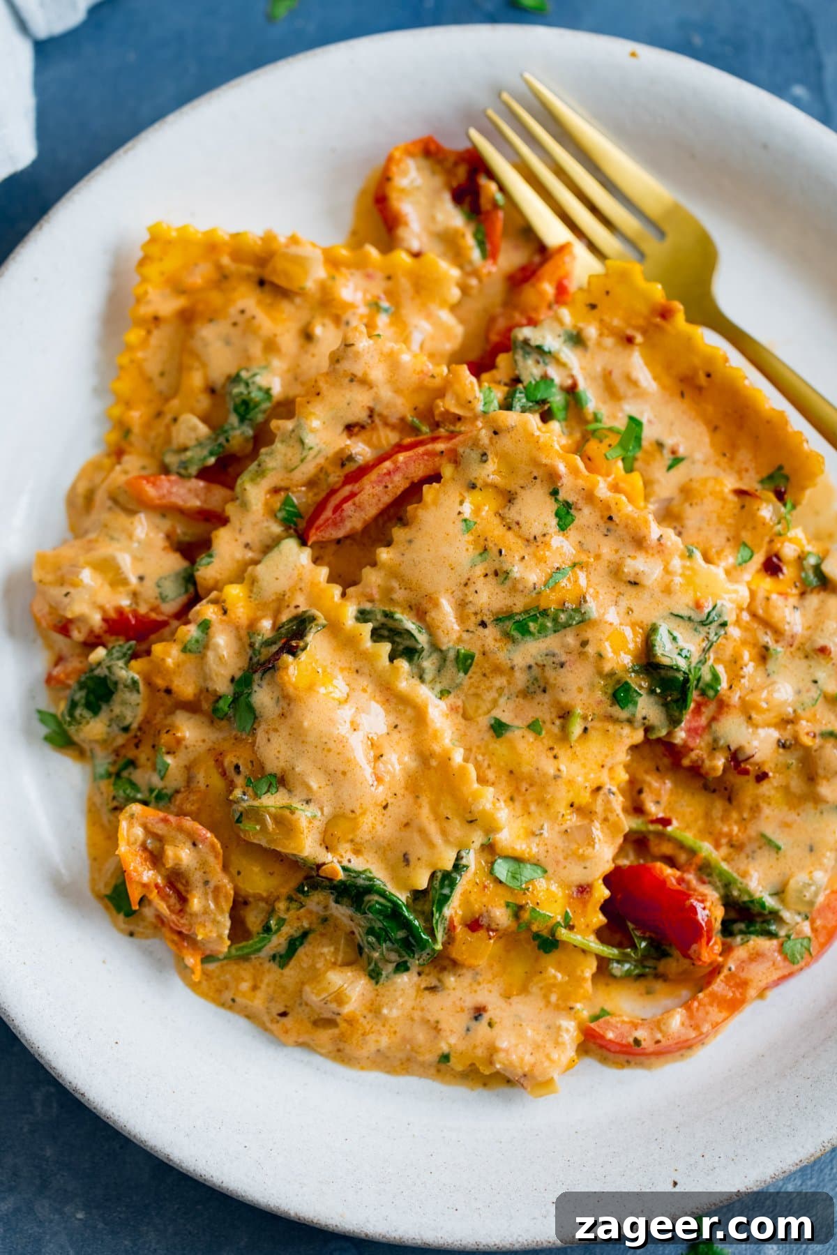 Creamy Tomato Sauce for Ravioli: Quick Weeknight Recipe 9 Ravioli in creamy tomato sauce on a white plate with a gold fork