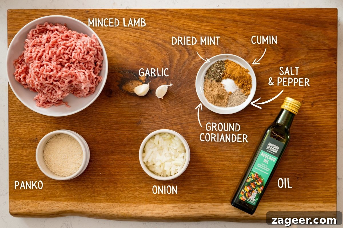 lamb kofta ingredients A wooden board displays the key ingredients for a Lamb Kofta Recipe: minced lamb, panko breadcrumbs, chopped onion, garlic cloves, spices such as dried mint and cumin, salt and pepper, plus a bottle of oil—perfect for preparing delicious lamb kofta.