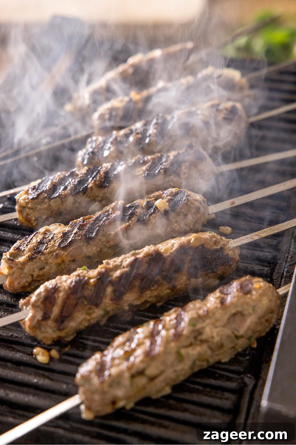 Authentic Lamb Kofta Recipe with Tangy Yogurt Sauce 5 Lamb koftas being cooked on a griddle with steam rising.