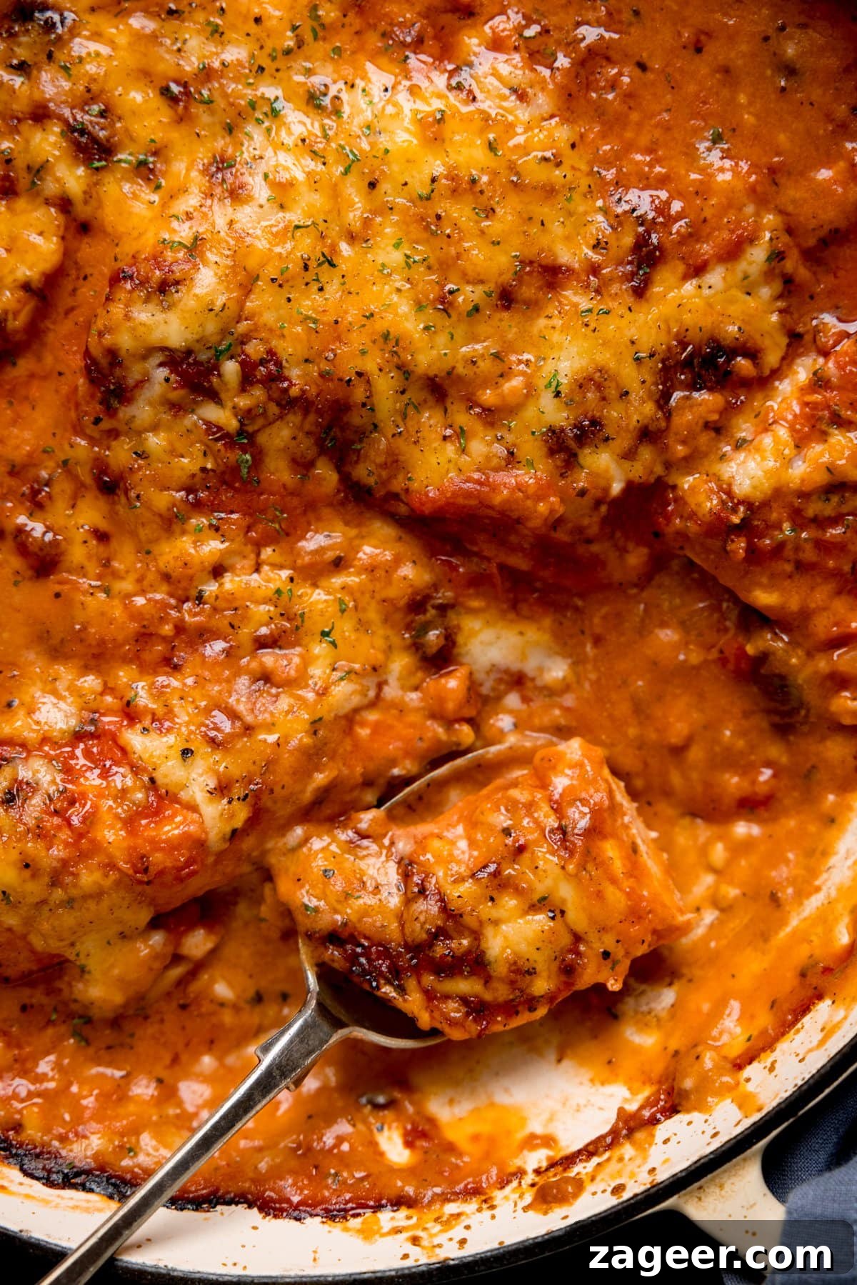 Lasagna-Style Baked Chicken Casserole Recipe 6 Close up of a spoonful of chicken being taken from a pan of lasagne-style chicken bake.