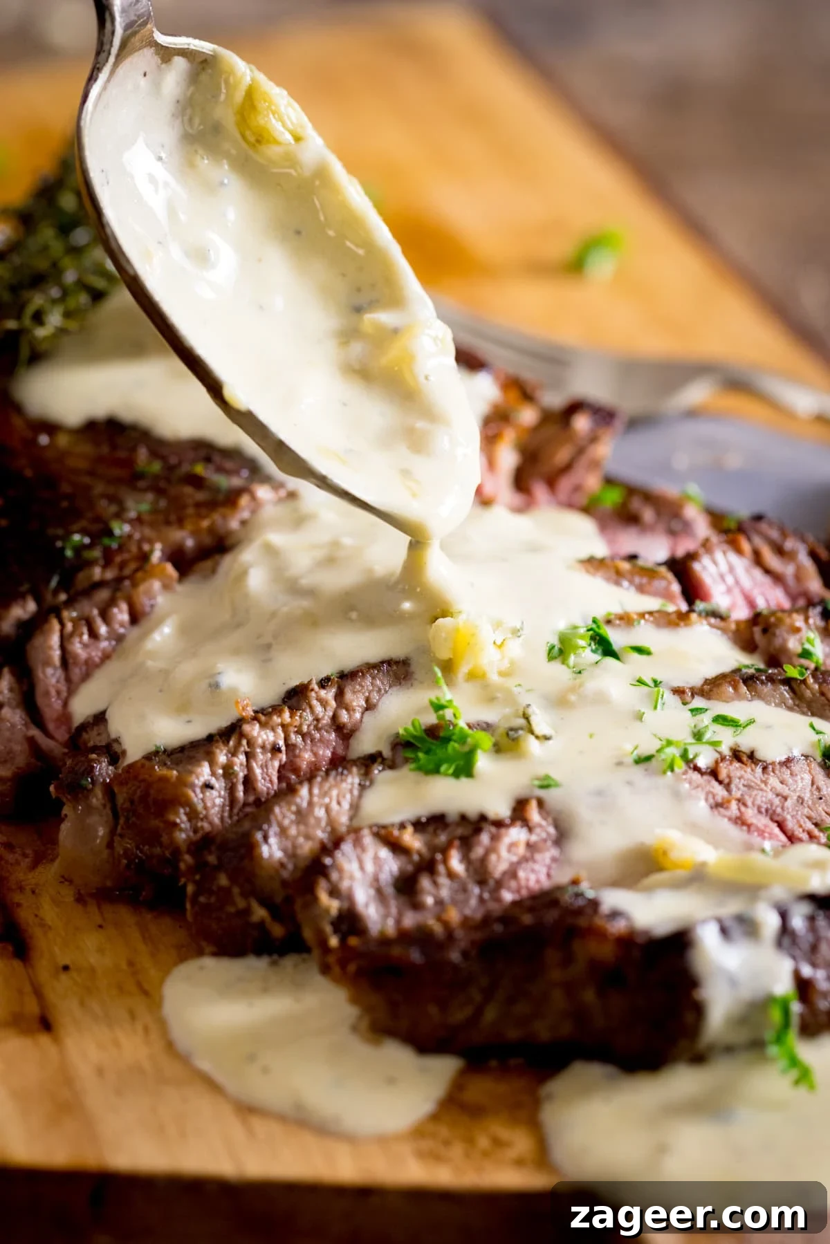 Creamy Blue Cheese Sauce Recipe for Steak and Wings 5 A steak with a blue cheese sauce being poured over it from a spoon