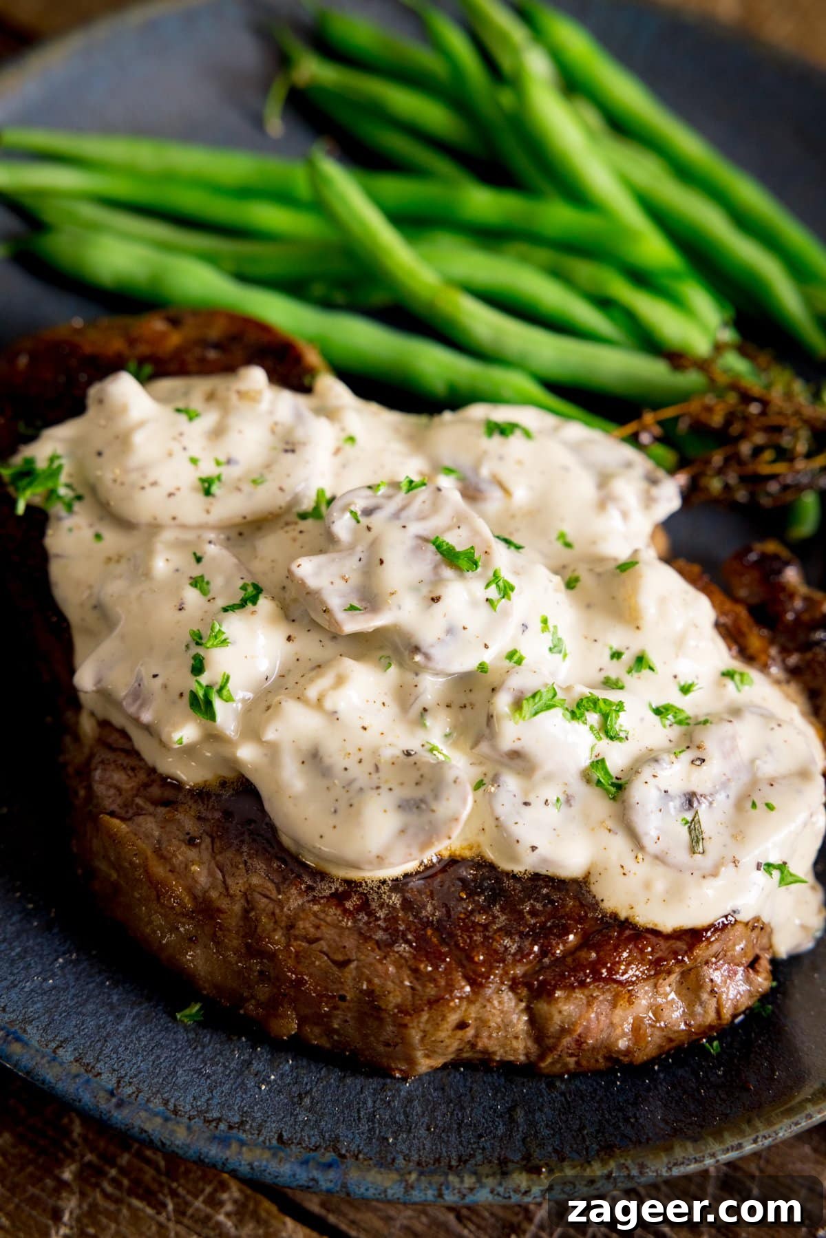 Creamy Mushroom Sauce Recipe for Pasta, Steak & Chicken 6 A blue plate with creamy mushroom sauce on a cooked steak
