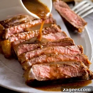 Rich Red Wine Jus Recipe for Steaks and Roasts 12 Sliced and cooked steak with red wine jus being poured over the top from a white jug
