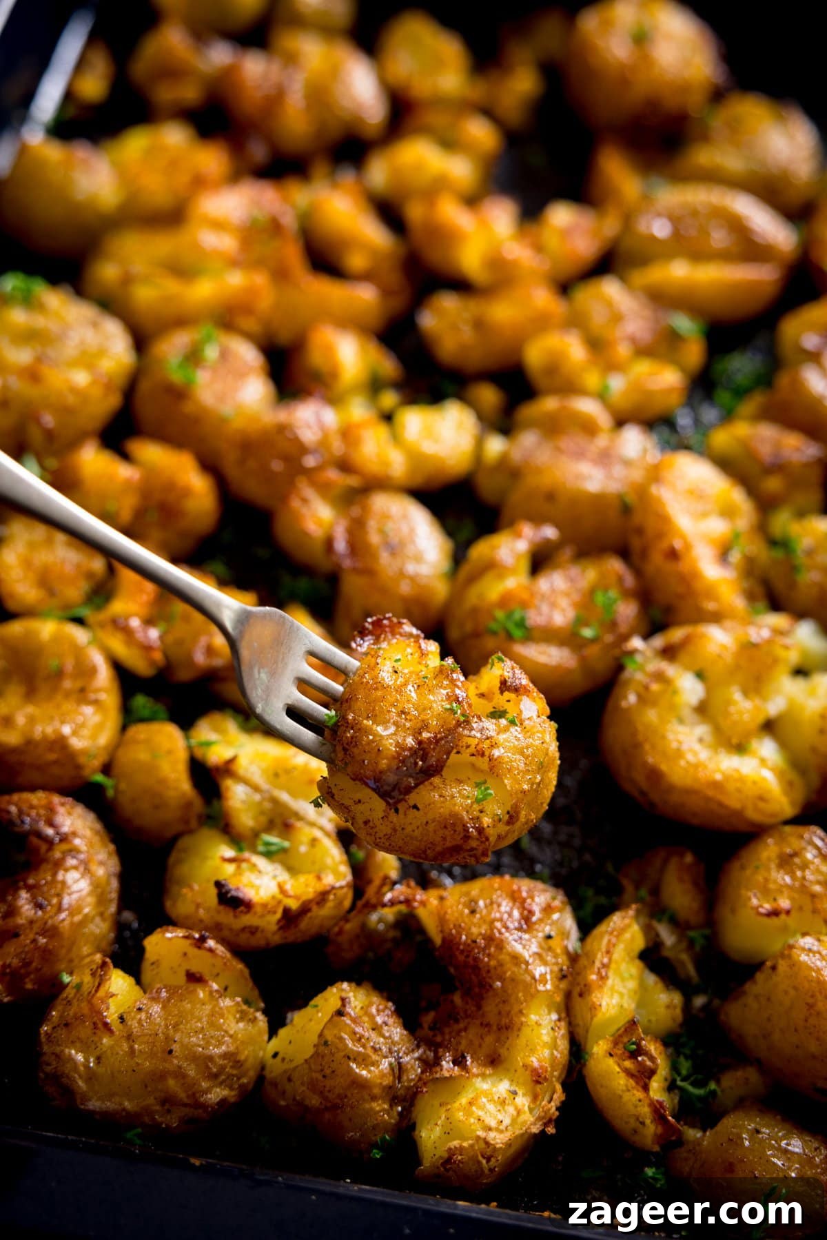 Crispy Garlic Smashed Potatoes Recipe for Perfectly Crispy Skins 2 A fork digging into a big tray of crispy smashed potatoes