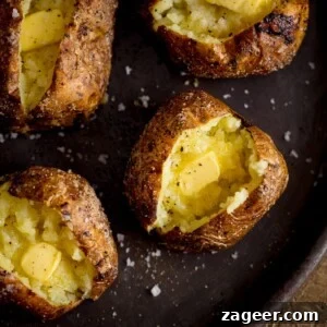 Perfectly Crispy Baked Potato: Foolproof Oven Method 12 Square overhead image of four open baked potatoes, with butter, on a tray.